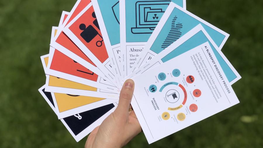 Een hand toont de AI Blindspot kaartenset van MIT (original)