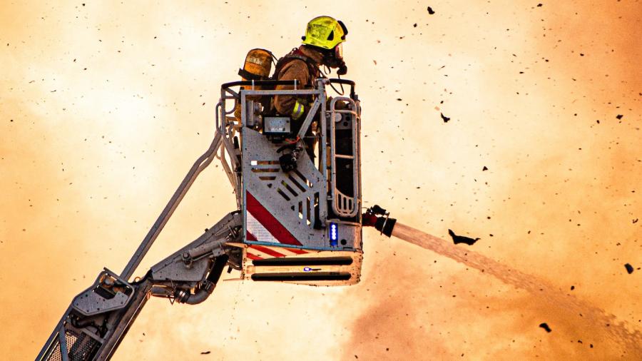 Brandweermannen bestrijden een bedrijfsbrand vanuit een kraan