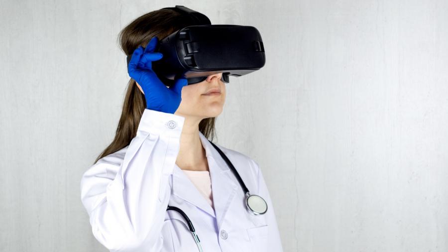 Onderzoekster met witte jas en stethoscoop werkt met een VR-bril op het hoofd