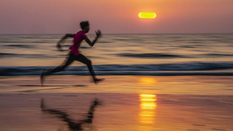 Man loopt op het strand bij zonsondergang