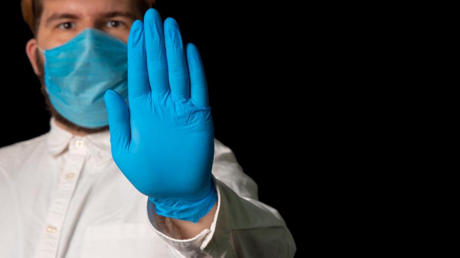 Dokter met mondmasker en handschoenen zegt stop