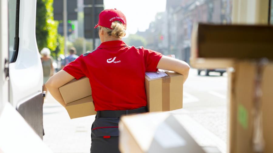 Een postbediende bezorgt pakketjes in de stad