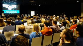 Ondernemers luisteren in een grote zaal naar een spreker tijdens een AI4Growth conferentie