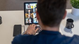 Een man overlegt in zijn thuiskantoor via videoconferencing met collega's