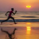 Man loopt op het strand bij zonsondergang